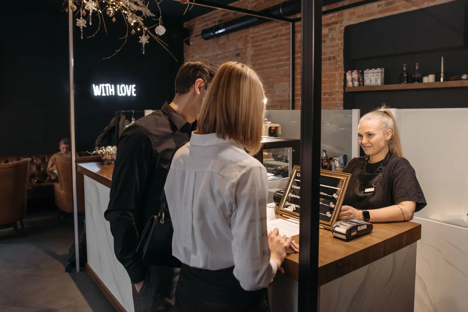 Un barista souriant à deux clients de l’autre côté du comptoir dans un café