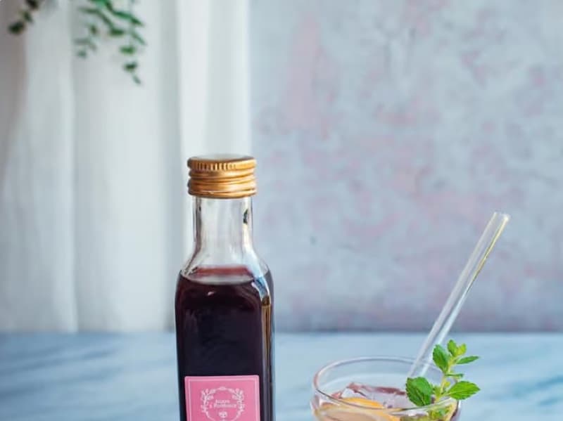 A bottle of raspberry syrup next to a glass