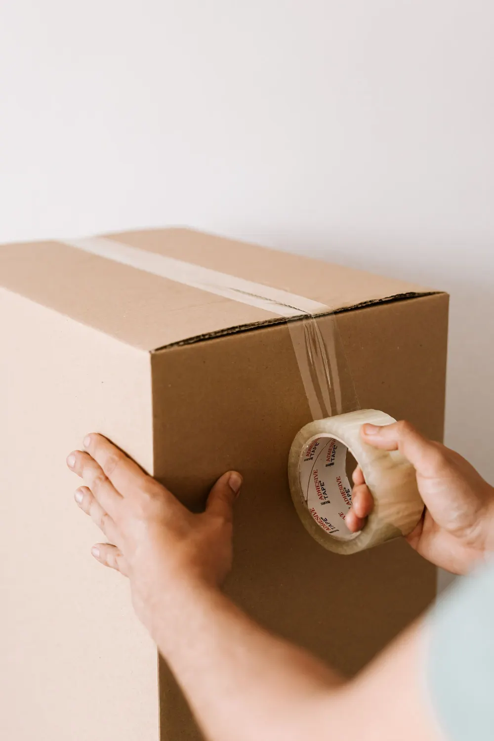 A parcel for the order being taped shut by hand.